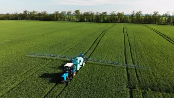 Letecký pohled na traktor, který zavlažuje zelené pole speciálním zařízením. Proces postřiku pesticidů a ochranou proti hmyzu hlodavců, parazitů a škůdců. — Stock video