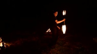 Düşük anahtar. Uzun saçlı genç erkek siyah bir gece video yavaş hareket açık meşale açık döner. Modern fakir yanan bir personel ile hileler yapar