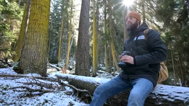 En skäggiga manliga resenären fotograf med sin kamera i vinterskogen tar bilder av naturen. Resekoncept för bloggare och foto konstnärer — Stockvideo