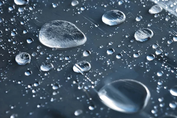 Close-up de gotas de chuva de diferentes tamanhos na superfície coberta com filme aderente. Tempo de umidade e conceito de umidade — Fotografia de Stock