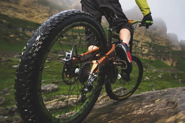 Vista posteriore grandangolare in parte un uomo in mountain bike viaggia su terreni rocciosi. Il concetto di mountain bike e mtb downhill — Foto Stock