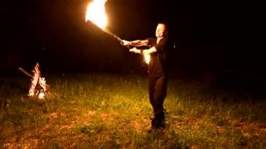 Düşük anahtar. Uzun saçlı genç erkek siyah bir gece video yavaş hareket açık meşale açık döner. Modern fakir yanan bir personel ile hileler yapar