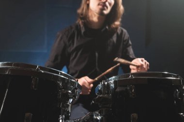 Drum stick'li bulanık bir odak dışı davulcuya karşı bir davul setinin yakın çekim detayı