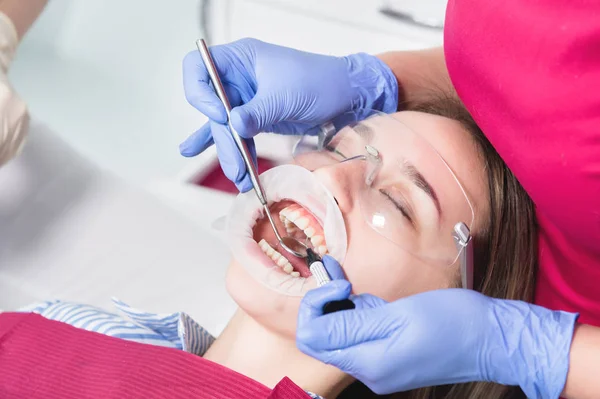 Κοντινό πλαίσιο ενός οδοντιάτρου που εφαρμόζει πολυμερές από μια σύριγγα στο εσωτερικό ενός νεαρού ασθενούς μπροστινό δόντι σε ένα οδοντιατρείο — Φωτογραφία Αρχείου