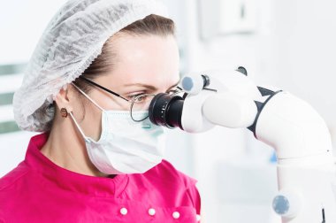 Yakın çekim Ofisinde profesyonel bir stamotolojik mikroskopla çalışan profesyonel bir diş hekimi olan gözlüklü bir kadın. Stamotoloji mesleği kavramı