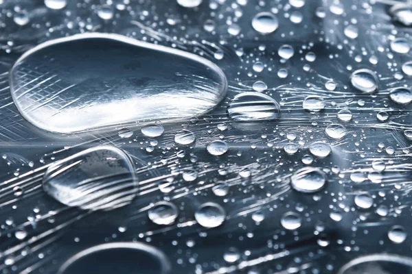 Närbild av regndroppar i olika storlekar på ytan täckt med plastfolie. Väder-och fuktighets koncept — Stockfoto