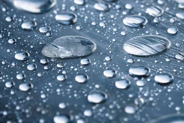 Close-up de gotas de chuva de diferentes tamanhos na superfície coberta com filme aderente. Tempo de umidade e conceito de umidade — Fotografia de Stock