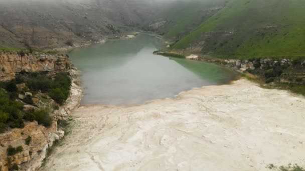 Vue aérienne lac turquoise de montagne parmi les collines par temps nuageux et brouillard. Paysages du Caucase du Nord 