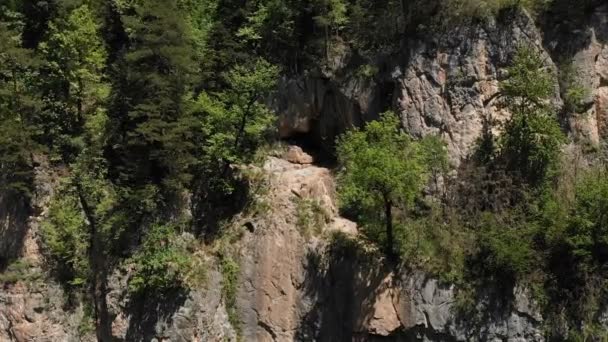 A man in a hat sits on the edge of a cliff in the lotus position and meditates contemplating infinity. Aerial view 4k — Stock Video