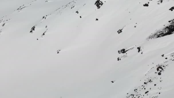 Luchtfoto van een Winterberg landschap. De met sneeuw bedekte rotsachtige hellingen van het resort van de zuidelijke regio Elbrus met skipistes op de sneeuw. Winter sport concept — Stockvideo