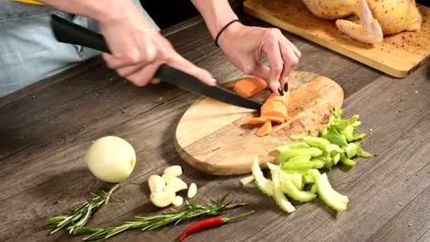 In Großaufnahme schneidet eine Köchin geschälte Möhren auf einem hölzernen Schneidebrett neben geschnittenem Gemüse. das Konzept des Vegetarismus — Stockvideo