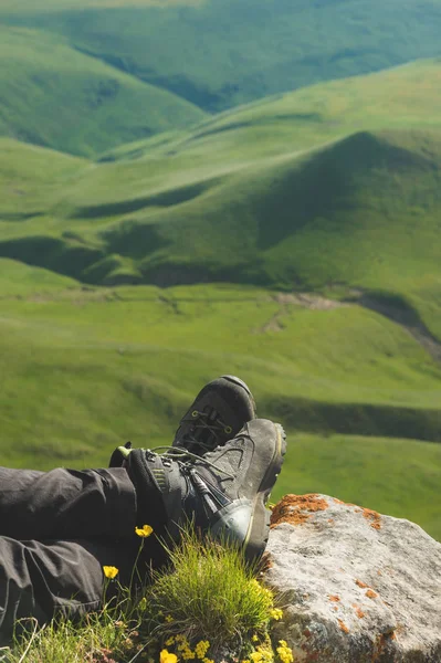 Una vista en primera persona POV de un hombre se sienta en el borde de un alto acantilado y disfruta del paisaje. Amplio ángulo humano pie trekking descanso. Concepto turístico — Foto de Stock