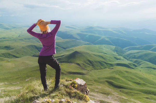 Hátulsó kilátás egy vonzó női turista állt egy füves dombon visel napszemüveg. Élvező nyári napsütéses napon a Kaukázusban. Aktív idegenforgalomra vonatkozó koncepció — Stock Fotó