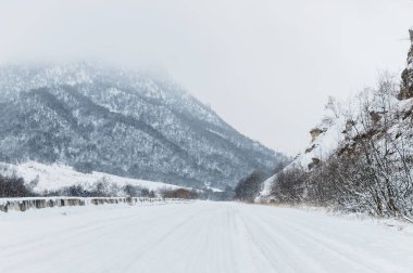 Kışın boş dağ asfalt yolu bulutlu bir günde karla kaplı. Kış buz ve seyahat bir araba sürüş kavramı