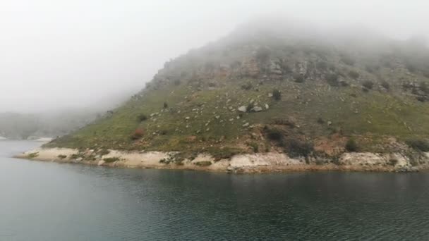 Vista aérea de uma costa rochosa. Montanha lago azul-turquesa entre as colinas em tempo nublado e nevoeiro. Paisagens do Norte do Cáucaso — Vídeo de Stock