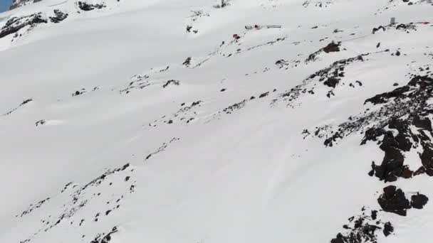 Letecký pohled na zimní horskou krajinu. Hotel Bivuak na zasněžené skalní svazích letoviska jižního Elbrus. Extrémní horské prázdniny — Stock video