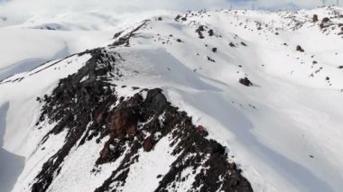 Bir kış dağ manzara havadan görünümü. Güney Elbrus bölgesinin karla kaplı kayalık yamaçlarında, karda kayak pistleri bulunmaktadır. Kış sporları konsepti