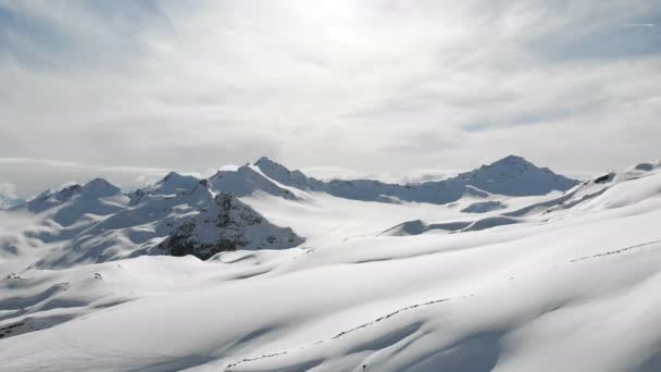 Vista aérea de un paisaje montañoso invernal. Las laderas rocosas cubiertas de nieve de la estación de la región sur de Elbrus con pistas de esquí en la nieve. Concepto de deportes de invierno — Vídeo de stock