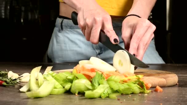 Primer plano de las manos de las cocineras rebanando cebollas en una tabla de cortar de madera junto a las verduras en rodajas. El concepto de vegetarianismo — Vídeos de Stock