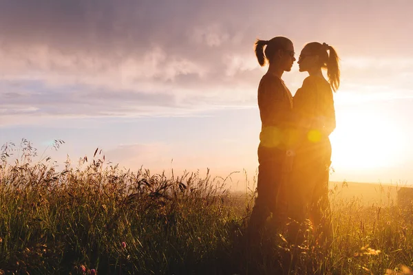 Retrato de silueta de una romántica pareja hipster joven de perfil. De pie en un abrazo sobre la naturaleza en la hierba alta El concepto de una familia joven y un futuro feliz juntos — Foto de Stock