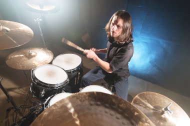 Ellerini bir davul seti arkasında oturan Chopsticks ile uzun saçlı bir davulcu portresi. Düşük anahtar. Milenyal nesil yaratıcı özgürlüğü kavramları