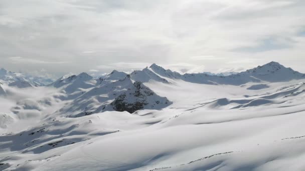 冬の山の風景の航空写真。雪に覆われた南エルブルス地域のリゾートの岩の斜面と雪の上にスキートラック。ウィンタースポーツコンセプト — ストック動画