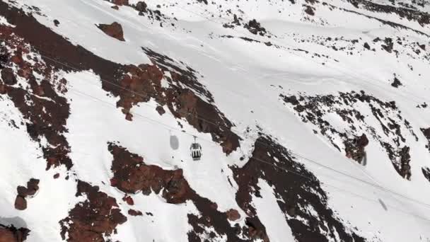 Kış sezonunda Elbrus beldesinde Kafkasya'nın yüksek dağlarında teleferik ve kayak pistlerinin havadan görünümü. Kabinlerin kablo yolunu izleme — Stok video