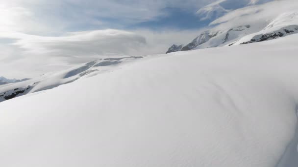 Vista aérea de uma paisagem de montanha de inverno. As encostas rochosas cobertas de neve do resort da região sul de Elbrus com pistas de esqui na neve. Conceito de esportes de inverno — Vídeo de Stock