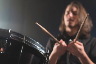 Drum stick'li bulanık bir odak dışı davulcuya karşı bir davul setinin yakın çekim detayı