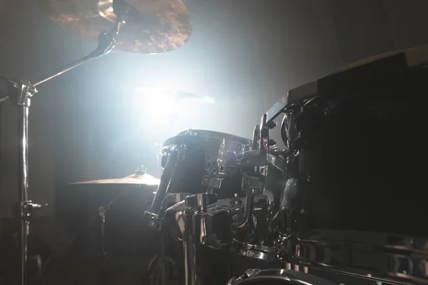 Close-up zwarte drums een moderne drumset voorbereid om te spelen in een donkere repetitieruimte op het podium met een heldere schijnwerper. Het concept van percussie muziekinstrumenten — Stockfoto
