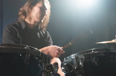 Drum stick'li bulanık bir odak dışı davulcuya karşı bir davul setinin yakın çekim detayı