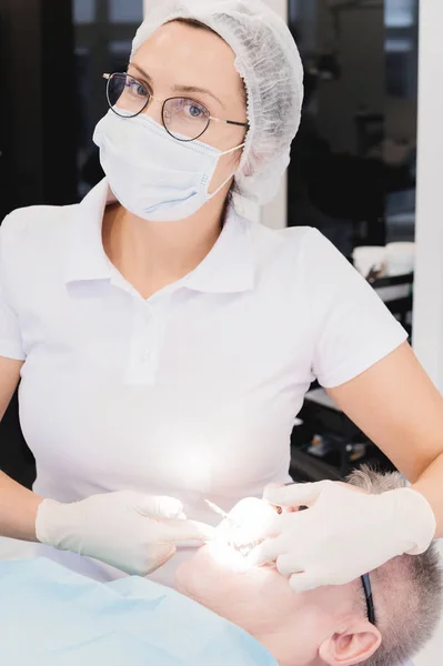 Πορτρέτο ενός γυναικείου οδοντίατρου στην εργασία φορώντας χειρουργικές μάσκες και γυαλιά που εργάζονται με έναν ασθενή — Φωτογραφία Αρχείου