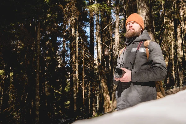 一个留着胡子的摄影师在冬天的针叶林中手拿反光相机的肖像。照片旅行概念 — 图库照片