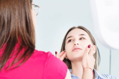 Dişçi kadın doktor bir tıbbi ofiste dişçi sandalyede oturan genç bir hasta konuşuyor. Müşteri ve dış görsel muayene ile ilk konuşma