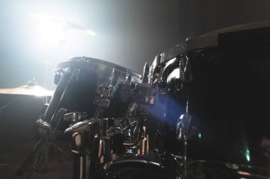 Yakın çekim siyah davul parlak bir spot ile sahnede karanlık bir prova odasında oynamaya hazırlanan modern bir davul seti. Perküsyon müzik aletleri kavramı