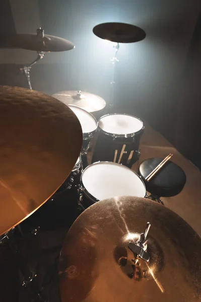 Conjunto de tambores moderno preparado para tocar em uma sala de ensaio escura no palco com um holofote brilhante. O conceito de instrumentos musicais de percussão de todas as direções musicais — Fotografia de Stock