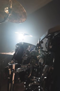 Yakın çekim siyah davul parlak bir spot ile sahnede karanlık bir prova odasında oynamaya hazırlanan modern bir davul seti. Perküsyon müzik aletleri kavramı