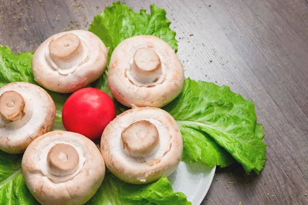 Primer plano de champiñones blancos con hojas de ensalada verde con tomate sobre una mesa de madera oscura. Comida vegetariana saludable — Foto de Stock