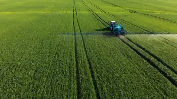 Vista aérea do trator que irriga o campo verde por instalação especial. O processo de pulverização de crescimentos de campo com pesticidas e proteção contra insetos de roedores, parasitas e pragas . — Vídeo de Stock