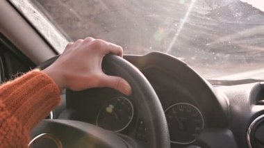 Şehir dışında bir araba sürüş turuncu bir kazak bir kadın elini yakın çekim. Yavaş hareket kadın araba kullanıyor