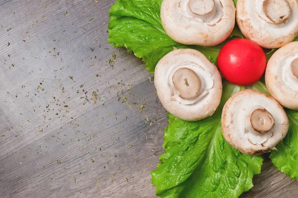 Primer plano de champiñones blancos con hojas de ensalada verde con tomate sobre una mesa de madera oscura. Comida vegetariana saludable — Foto de Stock