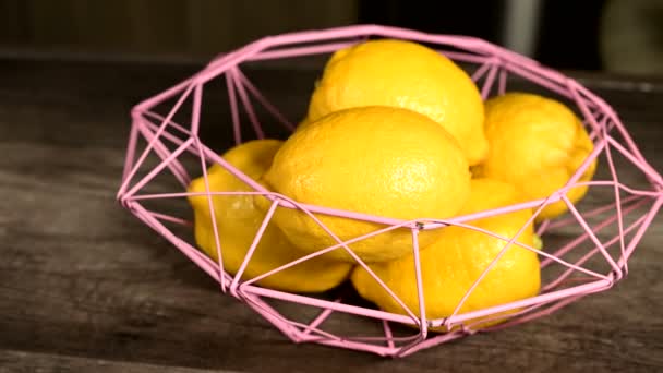 The concept of a healthy diet and natural products. Ripe yellow lemons lie in a wicker bowl on a dark wooden table home cooking. Close-up still life — Stock Video