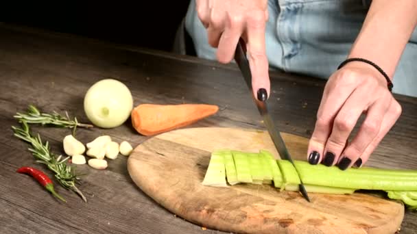 Primo piano delle mani femminili dello chef che affettano il sedano pelato su un tagliere di legno accanto alle verdure affettate. Il concetto di vegetarianismo — Video Stock