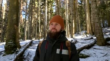 Bir gagalı genç adam bir sırt çantası ile bir iğne yaprak kış ormanda ayakta portresi