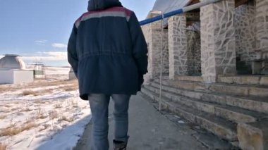 Kot ve sıcak bir üniforma bir erkek araştırmacı takip güneş Gözlemevi bilimsel binalar arasında bir kış güneşli bir gün kar üzerinden yürüyüş. Bilimsel Araştırma İstasyonu