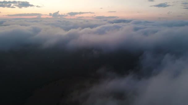 Vista aérea de baja altura vuelo nocturno sobre nubes y colinas en las montañas a la hora azul después de la puesta del sol. El concepto de fiesta nocturna y vuelos nocturnos fondo nublado. Movimiento hacia atrás — Vídeo de stock