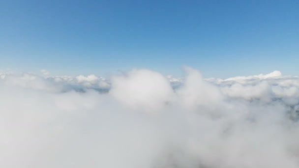 Flygvy dagtid flygning över och genom molnen och kullarna i bergen på en solig dag. Begreppet dagtid flygningar i bergen molnigt bakgrund — Stockvideo