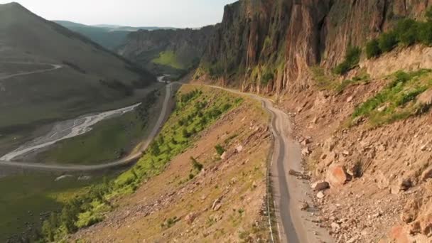 Vista aérea vuelo bajo primer plano en un paisaje con un camino de montaña asfalto serpentina en un profundo desfiladero. El concepto de comunicaciones de transporte en zonas montañosas remotas — Vídeo de stock