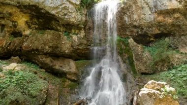 Bir yaz ormanındaki şelalenin panoramik manzarası. Su uçurumdan düşer. İnsanlar olmadan Peyzaj seyahat video