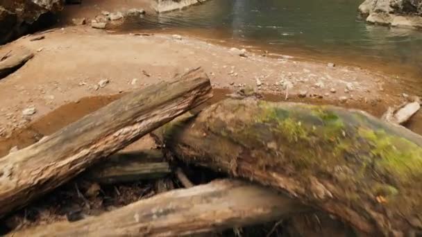 Vista aérea de un viajero masculino con una mochila de pie sobre las rocas frente a una majestuosa cascada y admirando la naturaleza en el bosque entre las rocas. Viajes video 4k — Vídeo de stock